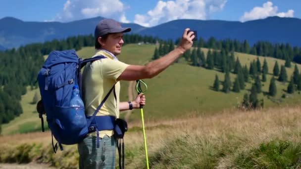 Een man vindt een panorama van de bergen op zijn telefoon. Wandelen, toerisme, bergen — Stockvideo