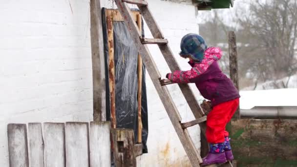 Het kind klimt de trap in de winter in het dorp. — Stockvideo