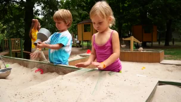 Niño y niña jugando con arena en el patio — Vídeos de Stock