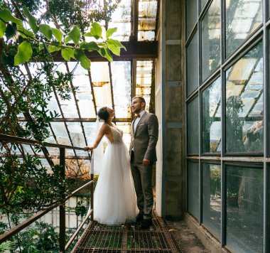 Evdeki düğün çifti birbirine sarılıyor. Beyaz elbiseli güzel bir kız. Takım elbiseli adam. Damat ile güzel gelin.