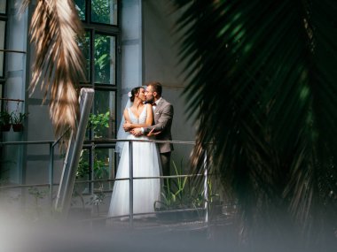 Evdeki düğün çifti birbirine sarılıyor. Beyaz elbiseli güzel bir kız. Takım elbiseli adam. Damat ile güzel gelin.