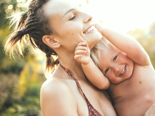 젊은 현대 어머니는 그녀의 팔에 그녀의 아들을 보유 하고있다. 여름 날에 일몰 사진 — 스톡 사진