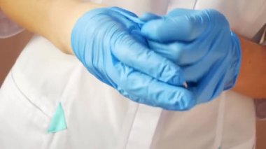 Yakın çekim doktorların ellerini gösteriyor. Kadın doktor eldivenlerini çıkarıyor.