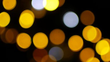 Defokusdaki çelenklerin sarı ışıkları bokeh gibi yanıp sönüyor.