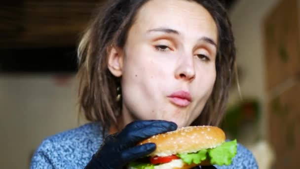 Joven chica hipster caucásica está comiendo una jugosa hamburguesa vegetariana y bailando — Vídeos de Stock