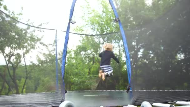 Ragazza che salta su un trampolino che si trova nel parco tra gli alberi — Video Stock