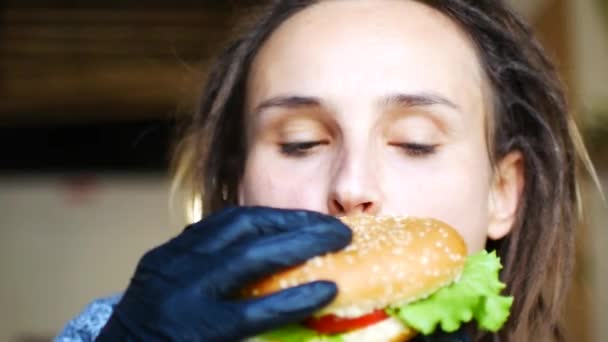 Jeune fille hipster caucasien mange un hamburger végétarien juteux et danse — Video