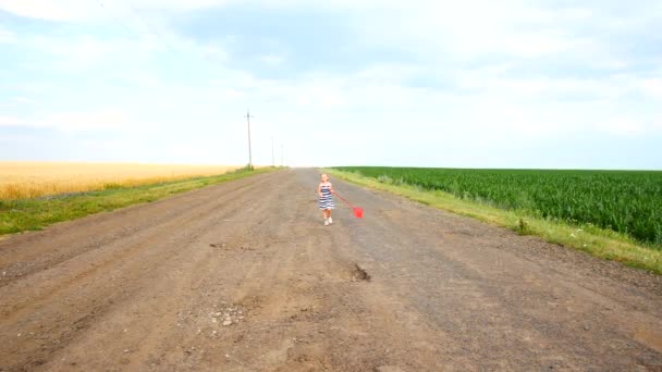 Menina caminhando ao longo de uma estrada rural — Vídeo de Stock