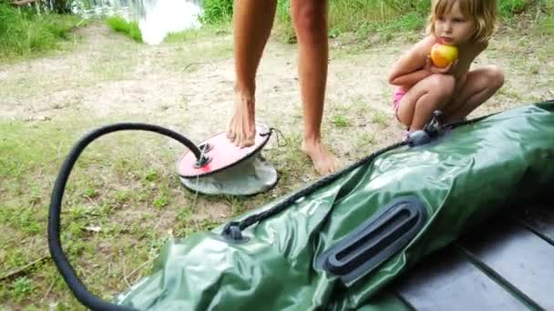 한 여성이 발 펌프로 팽창식 보트를 펌핑하고 있습니다.. — 비디오