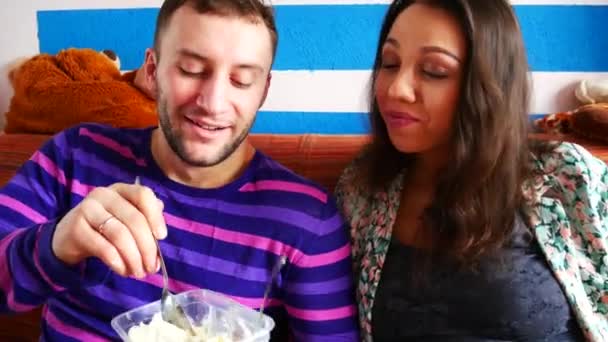 Mladí manželé se navzájem krmí zmrzlinou a sedí na pohovce — Stock video