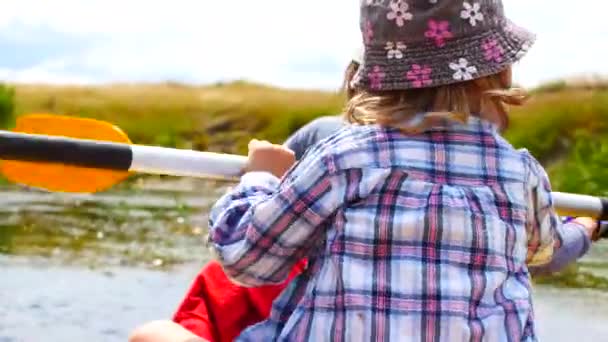 Een kind peddels op een kajak peddel. Actieve familie vakantie. — Stockvideo