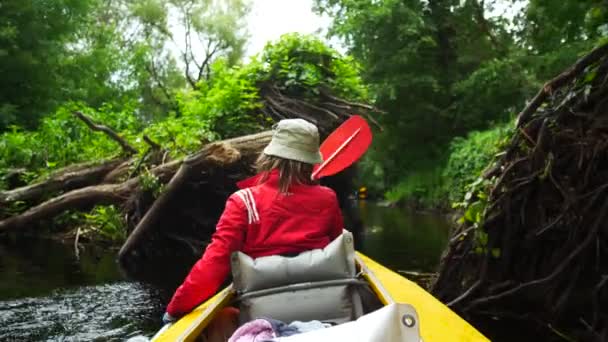 Pessoas irreconhecíveis, uma jovem trabalha duro com uma raquete em um caiaque no rio — Vídeo de Stock