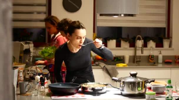 La señora prepara la comida en la cocina en compañía de sus amigos . — Vídeo de stock