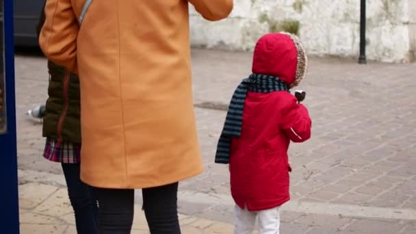 Das Mädchen isst Eis auf der Straße. Herbst, kühles Wetter. — Stockvideo