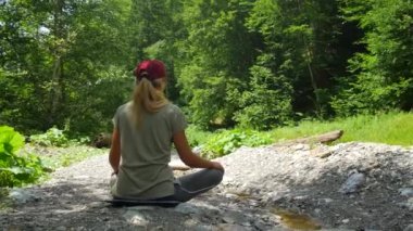 Beyaz bir kadın bir ormanda bir açıklıkta meditasyon. Saf doğada sakin.