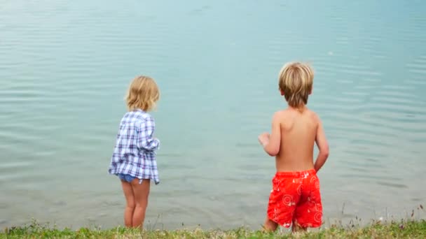 Childs brother and sister play near the lake — Stock Video