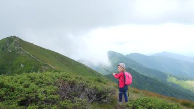 Çocuk kız dağın tepesine bir izleme çubuğu ile puan.