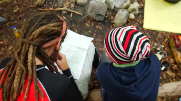 Turistas estão olhando para um mapa em um acampamento na floresta . — Vídeo de Stock