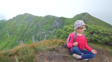 Bir çocuk bir dağın tepesinde lotus pozisyonunda meditasyon yapar..