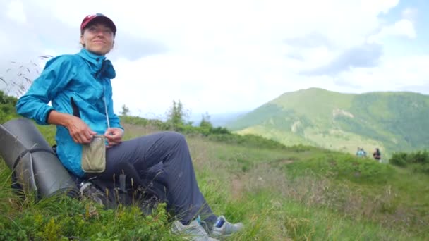 Meisje zitten rusten na het wandelen in de bergen — Stockvideo