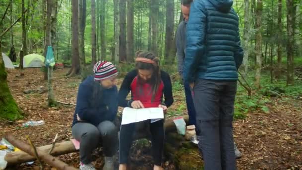 Туристи дивляться на карту в таборі в лісі . — стокове відео