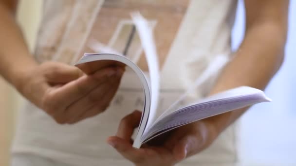 Estudante folheando através de um livro enquanto segurando nas mãos — Vídeo de Stock