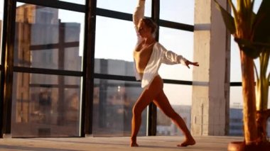 The girl is engaged in modern jazz ballet in a loft studio. A woman is spinning in a sunny room