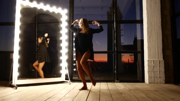 The girl slowly and sexually dances near a large mirror with bulbs — Stok video
