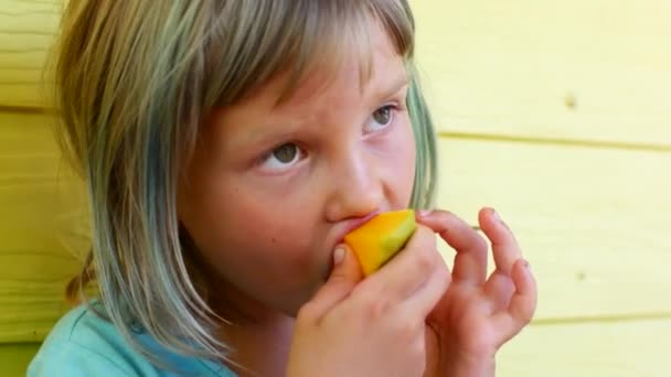 Девочка ест спелые манго — стоковое видео