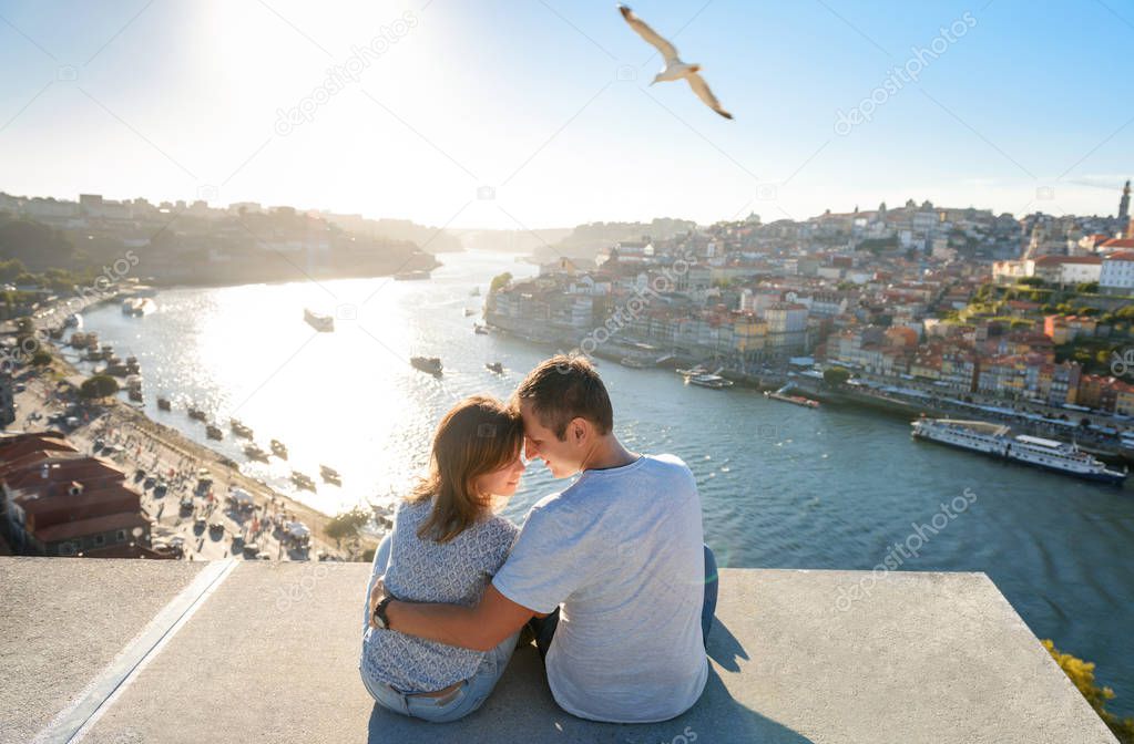 Couple relaxing on Porto in front of the skyline at sunset time