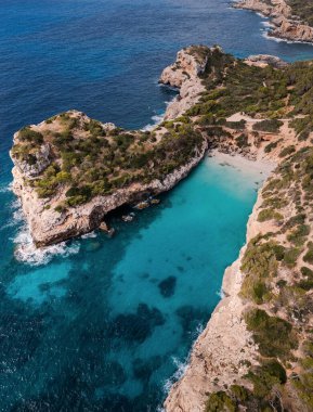 Turkuaz körfez kayalık kayalıklarla çevrili ve berrak Akdeniz sularıyla yemyeşil yemyeşil. Mayorka, Cala des Mora