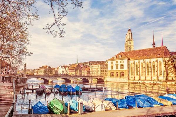 View of historic Zurich city center with famous Grossmunster Church and port with boats on quay of river Limmat, Canton of Zurich, Switzerland. Travel background with retro vintage instagram filter