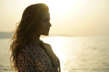 Sahilde günbatımı tarafından mutlu genç kadınla
