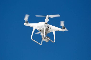 Profesyonel hava dron video kamera görüntüleri yukarıdan vuruyor. Büyük beyaz quadrocopter Uçak yüksekten mavi gökyüzünde uçuyor. Casus helikopter havada sinek kablosuz uzaktan kumanda ile