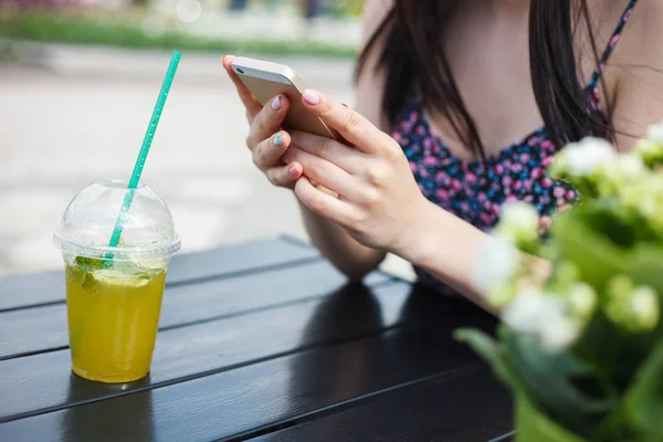 十几岁的女孩使用智能手机 Refreshin 莫吉托在塑料玻璃与稻草饮料 在炎热的夏日户外享受冷饮 年轻女子手里使用现代手机设备 — 图库照片