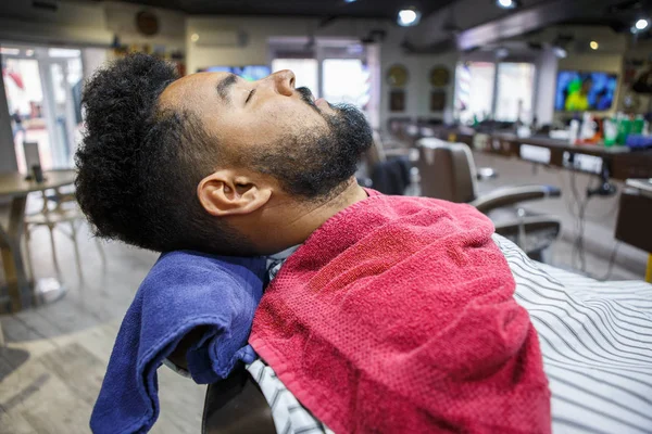 Jovem Homem Negro Cliente Deitado Cadeira Barbearia Espera Barbeiro Para — Fotografia de Stock