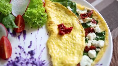 Bırakır dryed domates, Yunan beyaz peynir, taze yeşil ıspanak ile lezzetli omlet yemek brunch için kafede beyaz tabakta servis edilir. Restoran lezzetli doğal gıda öğle yemeği için. Omlet sabah tadını çıkarın.