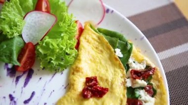Bırakır dryed domates, Yunan beyaz peynir, taze yeşil ıspanak ile lezzetli omlet yemek brunch için kafede beyaz tabakta servis edilir. Restoran lezzetli doğal gıda öğle yemeği için. Omlet sabah tadını çıkarın.