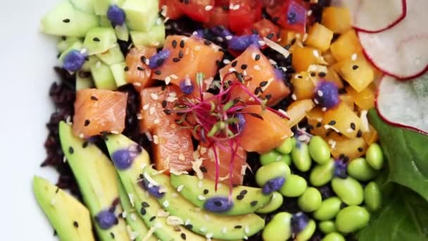 おいしい新鮮なサラダ サーモン グリーン豆 カフェでテーブルの上の白いボウル皿にアボカド 黒のご飯をスライスします レストランで昼食のための自然食品の映像 豊かな味と健康的な栄養 — ストック動画