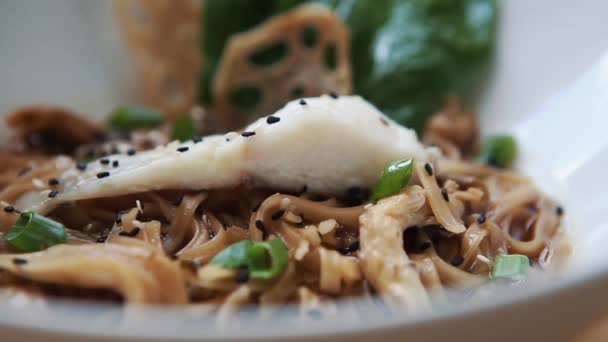 おいしいラーメン スープと白い海の低音の魚のフィレ ほうれん草の葉 アニス スパイス アジア レストランで白いボウル皿で提供しています カフェでランチのエキゾチックな食事をお楽しみください 食品の映像をアップします — ストック動画