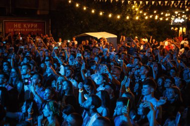 Kiev-11 Temmuz 2018: Grup yaz müzik festivali Bazat geceleri çekim akıllı telefonlar ile genç insan. Parlak mavi ışıklar kalabalıkta konser sahne alanı'nda ünlü müzisyenin fotoğraf çekmek