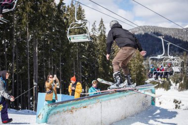 Bukovel, Ukrayna-24 Mart, 2018: Extreme Kayak jib yarışmaya kar park. Kayak binici demiryolu freeskis ile güneşli kış günde biler. Genç atlet dublör kısa kayaklar üzerinde gerçekleştirir.