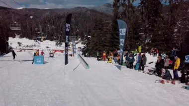 YAREMCHE, UKRAINE - 24 MARCH, 2018: Snowboarders & free ski riders take part in jib contest.Athletes grind on rail in Bukovel Snow Park.Extreme winter sport competition for young and active sportsmen.