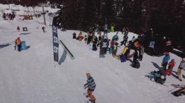 YAREMCHE, UKRAINE - 24 MARCH, 2018: Snowboarders & free ski riders take part in jib contest.Athletes grind on rail in Bukovel Snow Park.Extreme winter sport competition for young and active sportsmen.
