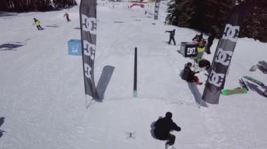 YAREMCHE, UKRAINE - 24 MARCH, 2018: Snowboarders & free ski riders take part in jib contest.Athletes grind on rail in Bukovel Snow Park.Extreme winter sport competition for young and active sportsmen.