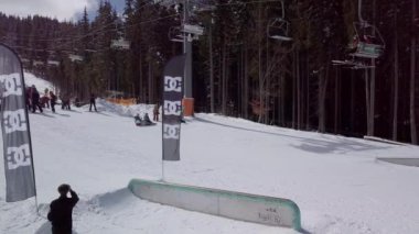 YAREMCHE, UKRAINE - 24 MARCH, 2018: Snowboarders & free ski riders take part in jib contest.Athletes grind on rail in Bukovel Snow Park.Extreme winter sport competition for young and active sportsmen.