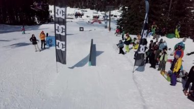 YAREMCHE, UKRAINE - 24 MARCH, 2018: Snowboarders & free ski riders take part in jib contest.Athletes grind on rail in Bukovel Snow Park.Extreme winter sport competition for young and active sportsmen.