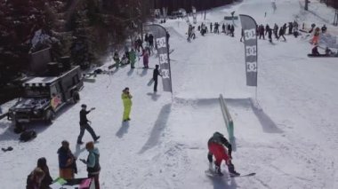 YAREMCHE, UKRAINE - 24 MARCH, 2018: Snowboarders & free ski riders take part in jib contest.Athletes grind on rail in Bukovel Snow Park.Extreme winter sport competition for young and active sportsmen.