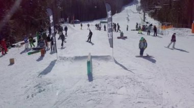 YAREMCHE, UKRAINE - 24 MARCH, 2018: Snowboarders & free ski riders take part in jib contest.Athletes grind on rail in Bukovel Snow Park.Extreme winter sport competition for young and active sportsmen.