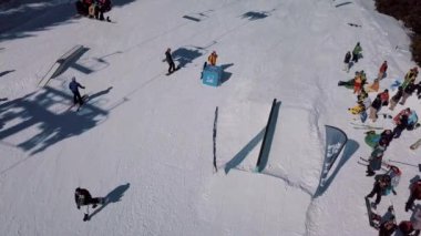 YAREMCHE, UKRAINE - 24 MARCH, 2018: Snowboarders & free ski riders take part in jib contest.Athletes grind on rail in Bukovel Snow Park.Extreme winter sport competition for young and active sportsmen.